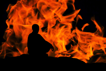 silhouette of a monk, meditating on fire backgroundの写真素材