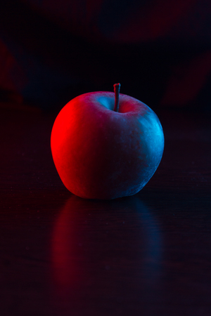 One apple on the table. Neon light. close upの写真素材