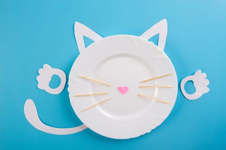 white plate on blue background with funny cat characterの写真素材