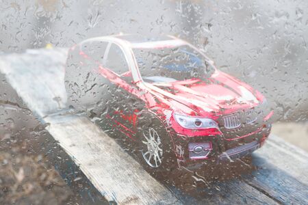 Red toy car outside in the rain. Childhood problems conceptの写真素材