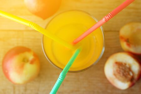 Peach juice on wooden background with strawsの写真素材