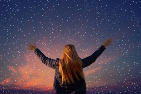 Woman with rased hand over night sky backgroundの写真素材