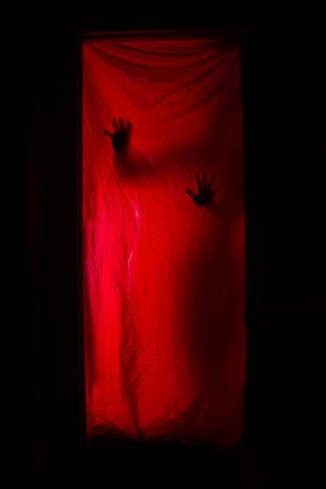 Silhouette of a woman behind red curtains. Horrorの写真素材