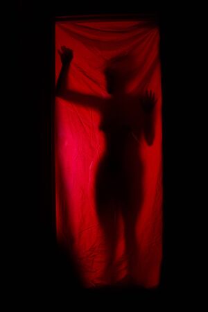 Silhouette of a woman behind red curtains. Horrorの写真素材