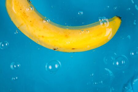 Banana falling into water on blue backgroundの写真素材