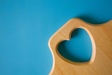 Wooden cutting board with heart shape on blue backgroundの写真素材