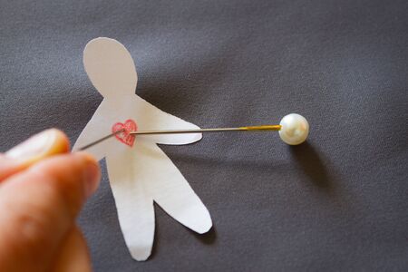 Paper voodoo doll on dark background with needlesの写真素材