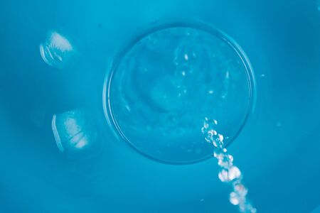 Glass of water on blue background in waterの写真素材