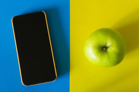 Smartphone and green apple on colorful backgroundの写真素材