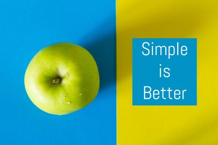 Single green apple on blue and yellow background