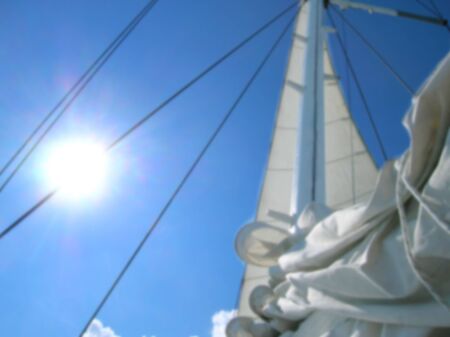 Blurred image of white sail over blue sky