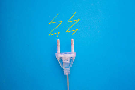 White electric plug on the blue background with copy spaceの写真素材
