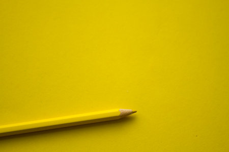 Yellow pencil on yellow background with copy space