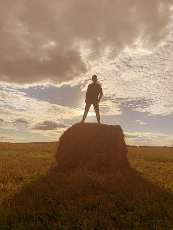 Man stand on stack of hey. Freedom conceptの写真素材
