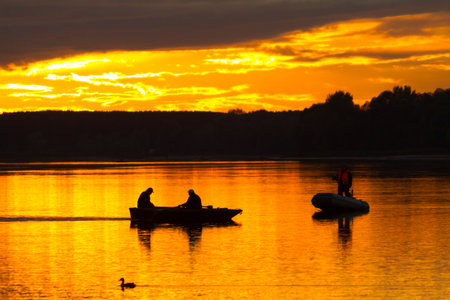 silhouette of fishermen on the boat at sunsetの写真素材