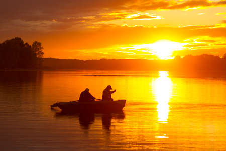 silhouette of fishermen on the boat at sunsetの写真素材