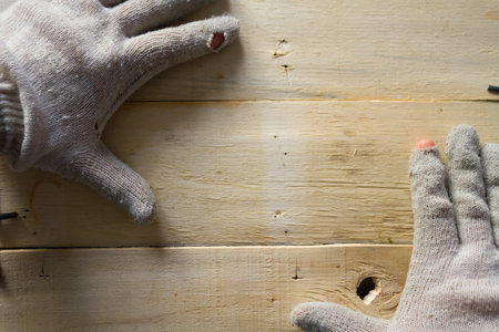 Hands in work gloves on wooden tableの写真素材