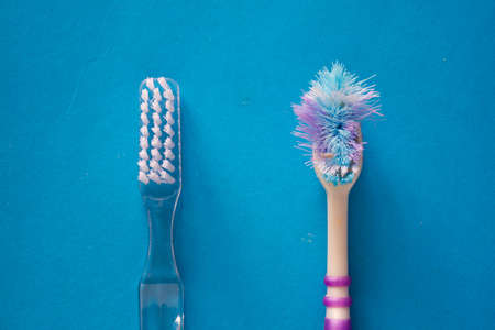 Two toothbrushes. One used and one new on blue backgroundの写真素材