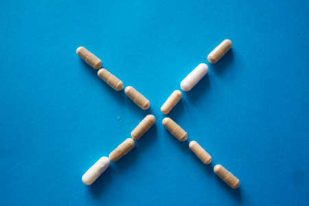 Cross made of pills on blue background. Trying to stop an addiction conceptの写真素材