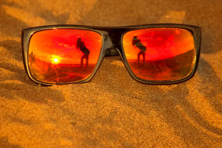 Reflection of a woman in sunglasses on the beachの写真素材