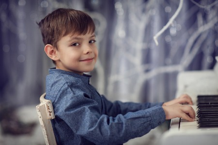 The boy in the blue shirt playing on a white pianoの写真素材