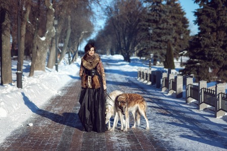 Woman walking a dog on the street in winterの写真素材