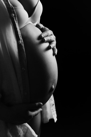Pregnant woman holding belly with hands. WB photoの写真素材