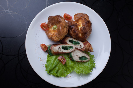 meat rolls on lettuce leaf. white plate on black tableの写真素材