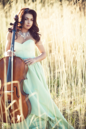 Girl with a cello in a tall grassの写真素材