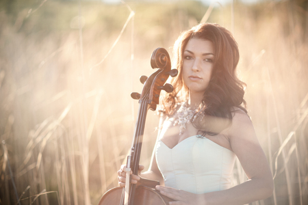 Girl with a cello in a tall grassの写真素材