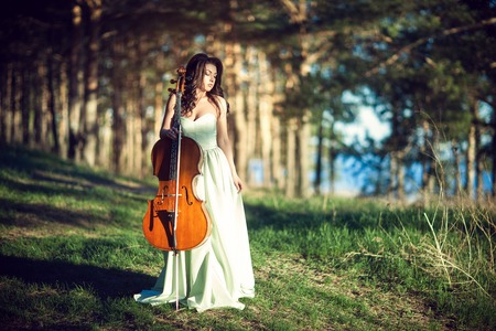 Woman with a cello in the woodsの写真素材