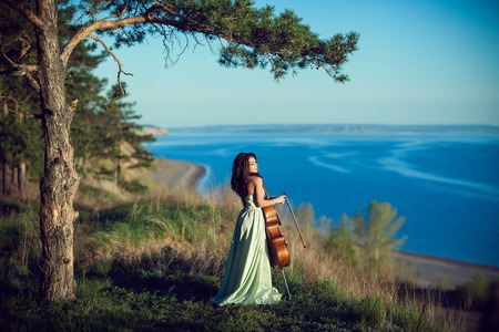 Woman with a cello in the woodsの写真素材