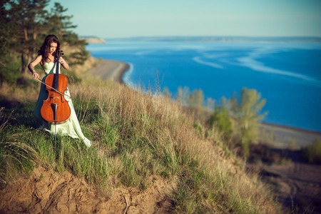 Woman with a cello in the woodsの写真素材