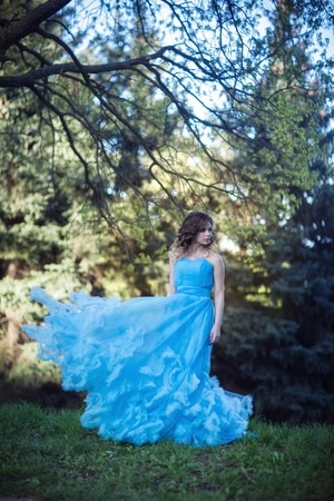 Young beautiful girl in a lush blue dressの写真素材
