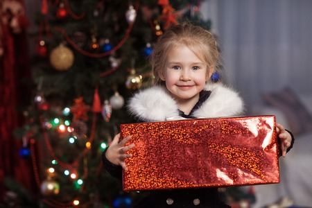 Joyful child with a gift near the Christmas treeの写真素材