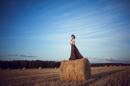 woman in a field with a straw in a Russian national costumeの写真素材