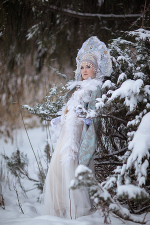 woman in a Snow Maiden costume in a winter forestの写真素材