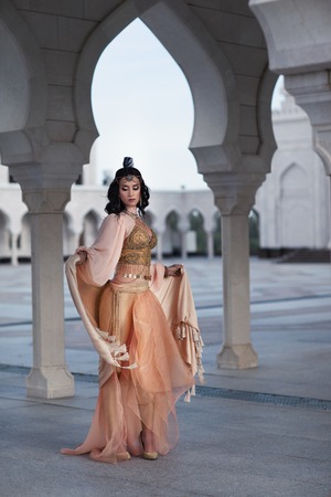 the woman in the peach dress on the white background of the mosque. Oriental style