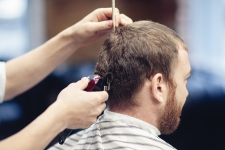 Barber shaves the client's head with a trimmer.の写真素材