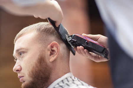 Barber shaves the client's head with a trimmer.の写真素材