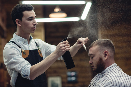 Barber splashes water on the client's hair. haircut in the salonの写真素材