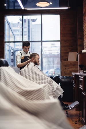 Salon barbershop. Barber and client in the chair against the windowの写真素材