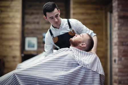 Barbershop. Barber's work. Barber shaves the client's beard with a shaving machineの写真素材