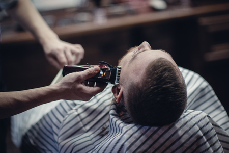 Barbershop. Barber's work. Barber shaves the client's beard with a shaving machineの写真素材