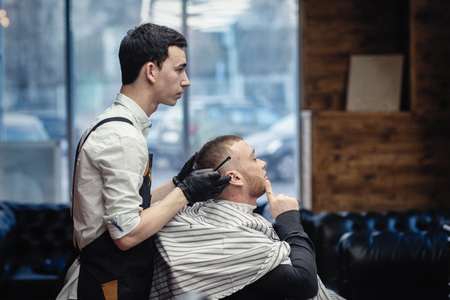 Salon barbershop. Barber and client in the chair against the windowの写真素材