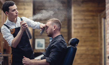 Barber splashes water on the client's hair. haircut in the salonの写真素材