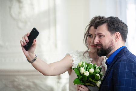 Joyful newlyweds make selfie. Lovers take pictures of themselves on the phoneの写真素材