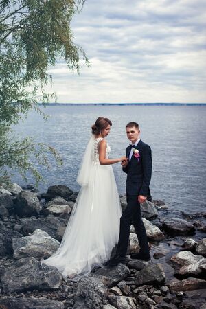 A pair of young newlyweds on the stones by the big riverの写真素材