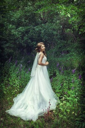 Wedding walk. Bride next to a green treeの写真素材