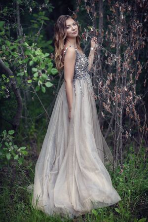 Photoshoot in a rainy forest. Girl in a beautiful dress near the treeの写真素材